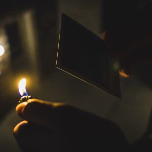 holding a burning match next to photograph